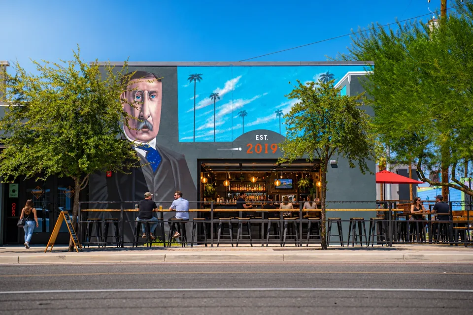 The Theodore mural and patio with an open bar entrance and guests